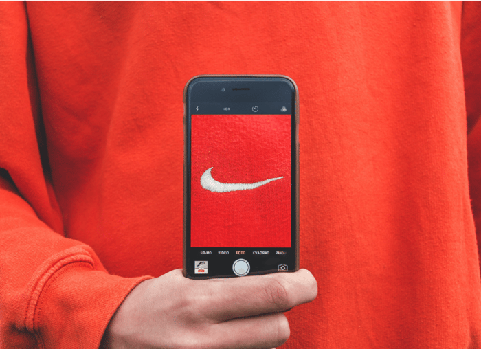 A person in a red Nike sweatshirt holding an iPhone taking a photo